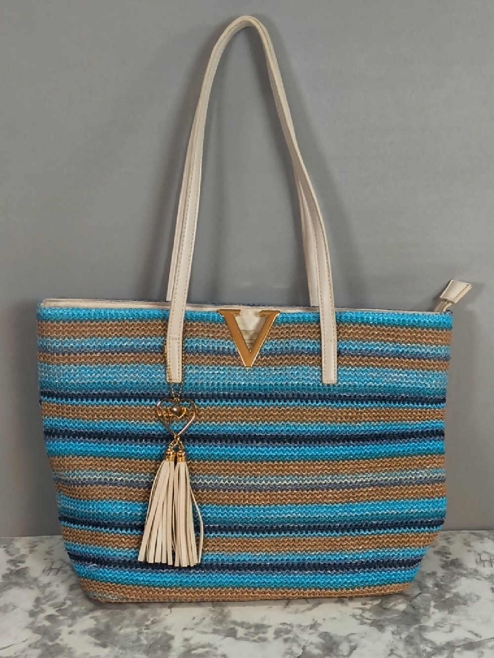 Crossi striped straw tote shoulder bag with a gold V accent and tassel charm